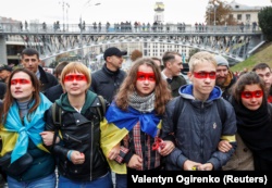 Учасники віча «Зупинимо капітуляцію!» із червоною лінією на обличчях під час здійснення «обходу» урядового кварталу. Київ, 6 жовтня 2019 року